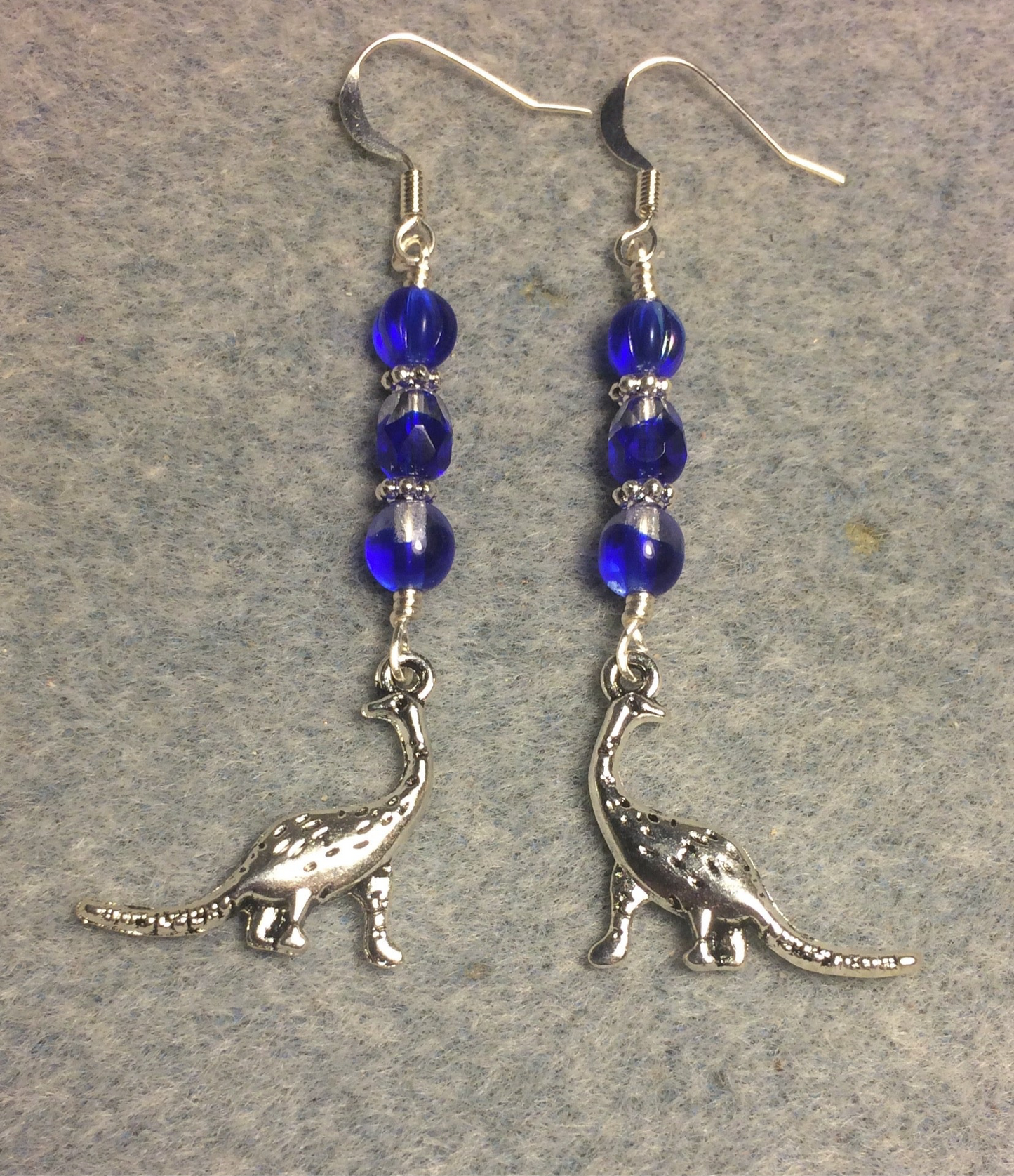Silver dinosaur charm earrings adorned with dark blue Czech glass beads