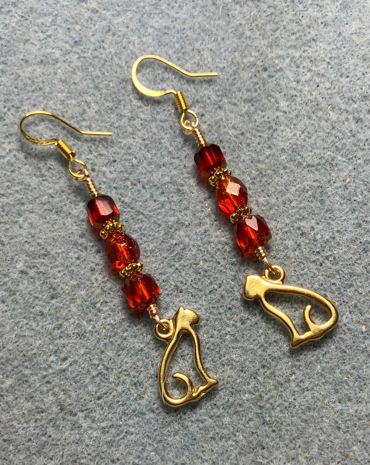 Gold silhouette cat charm earrings adorned with red Czech glass beads