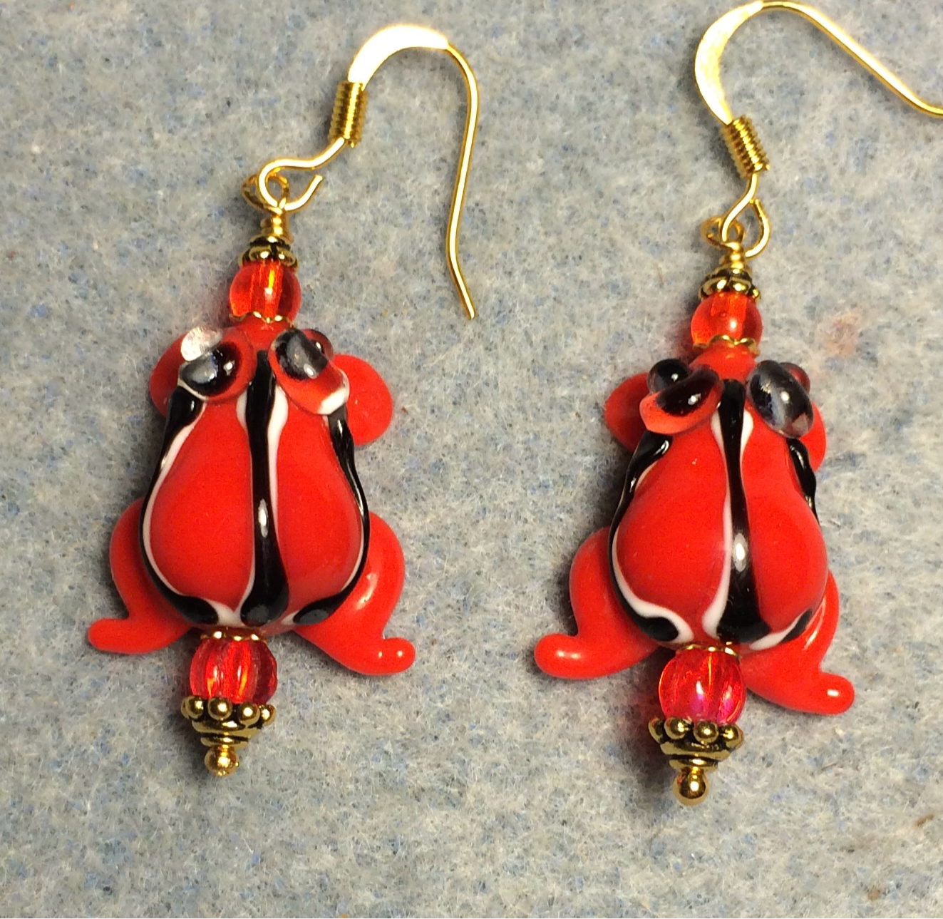 Opaque bright red lamp work striped frog bead earrings adorned with bright red Czech glass beads.
