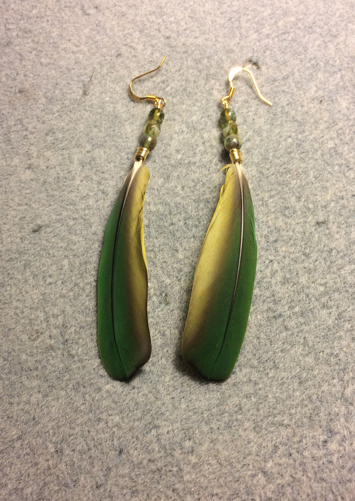 Green mini macaw feather earrings adorned with green Czech glass beads.