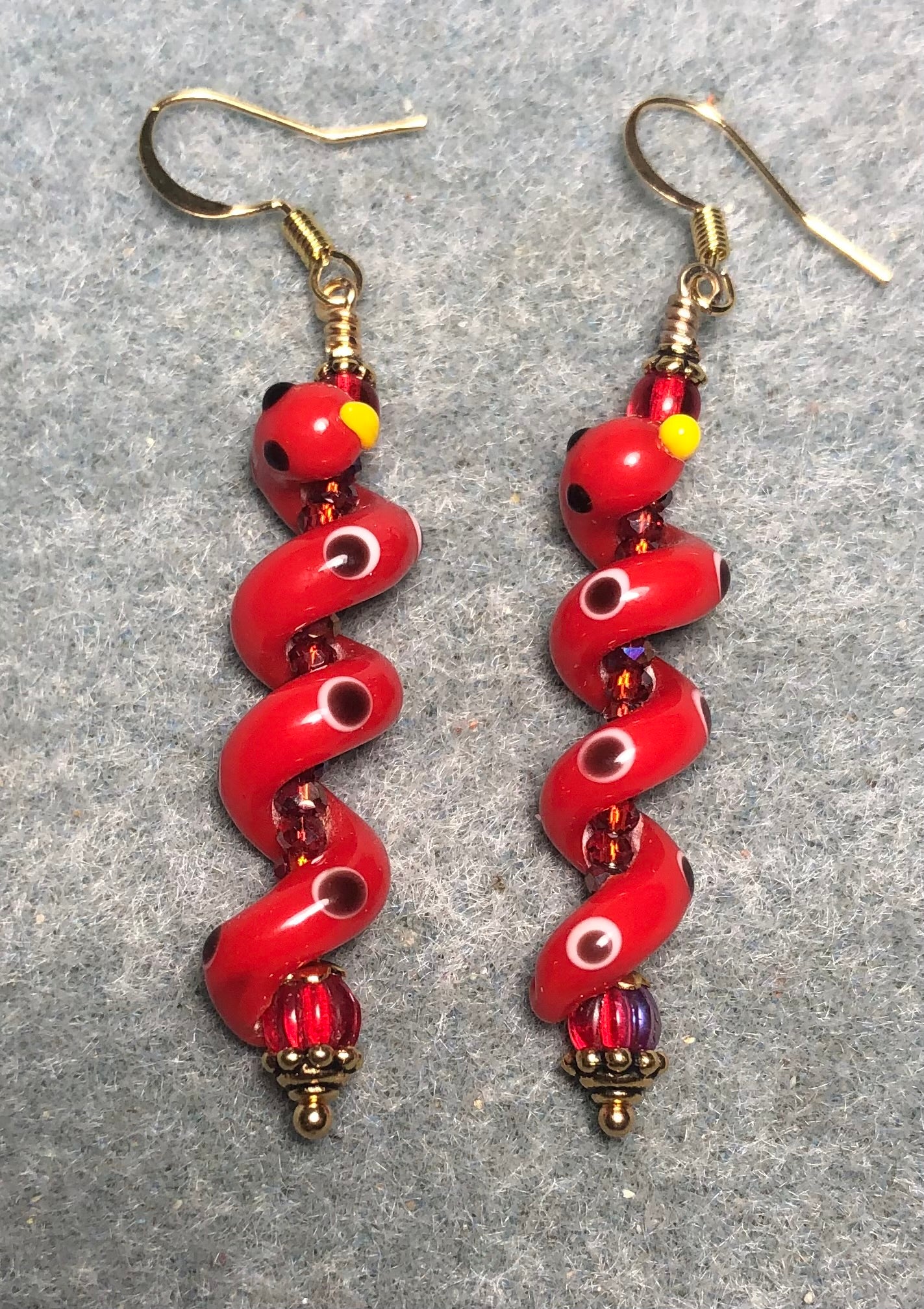Red lamp work coiled snake bead earrings adorned with red Czech glass beads and tiny red Chinese crystal beads.