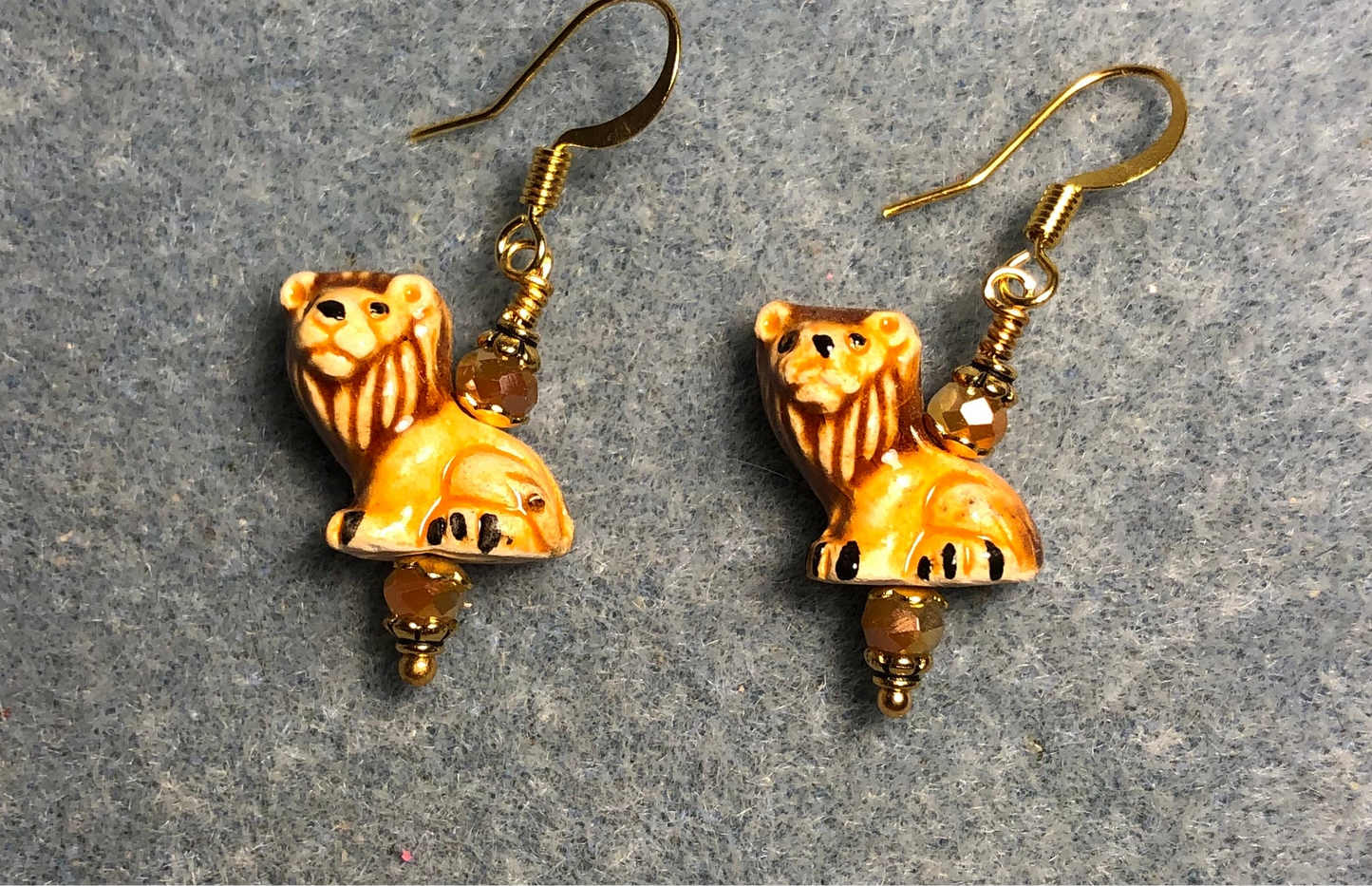 Tiny amber ceramic lion bead earrings adorned with tan Chinese crystal beads.