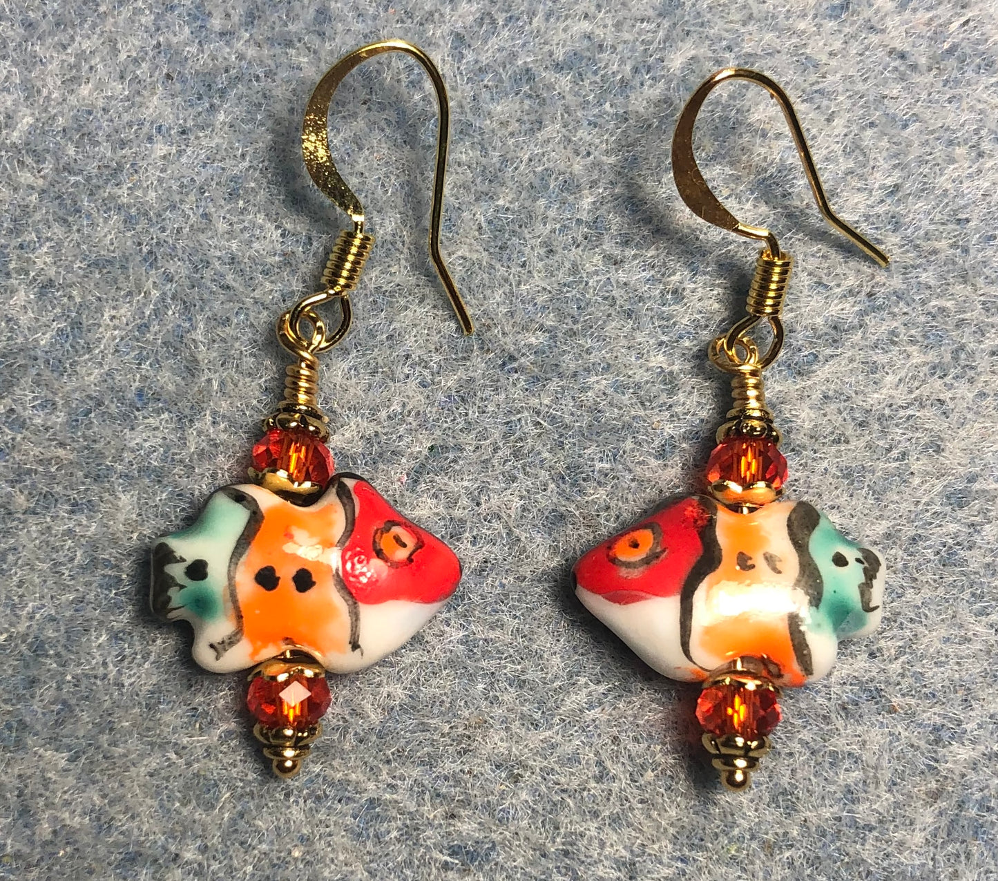 Small red, orange, and turquoise ceramic fish bead earrings adorned with orange Chinese crystal beads.