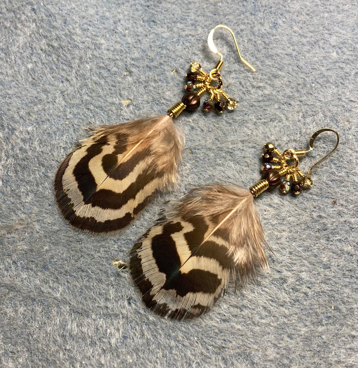 Brown and beige striped peacock body feather earrings adorned with tiny dangling brown Czech glass beads.