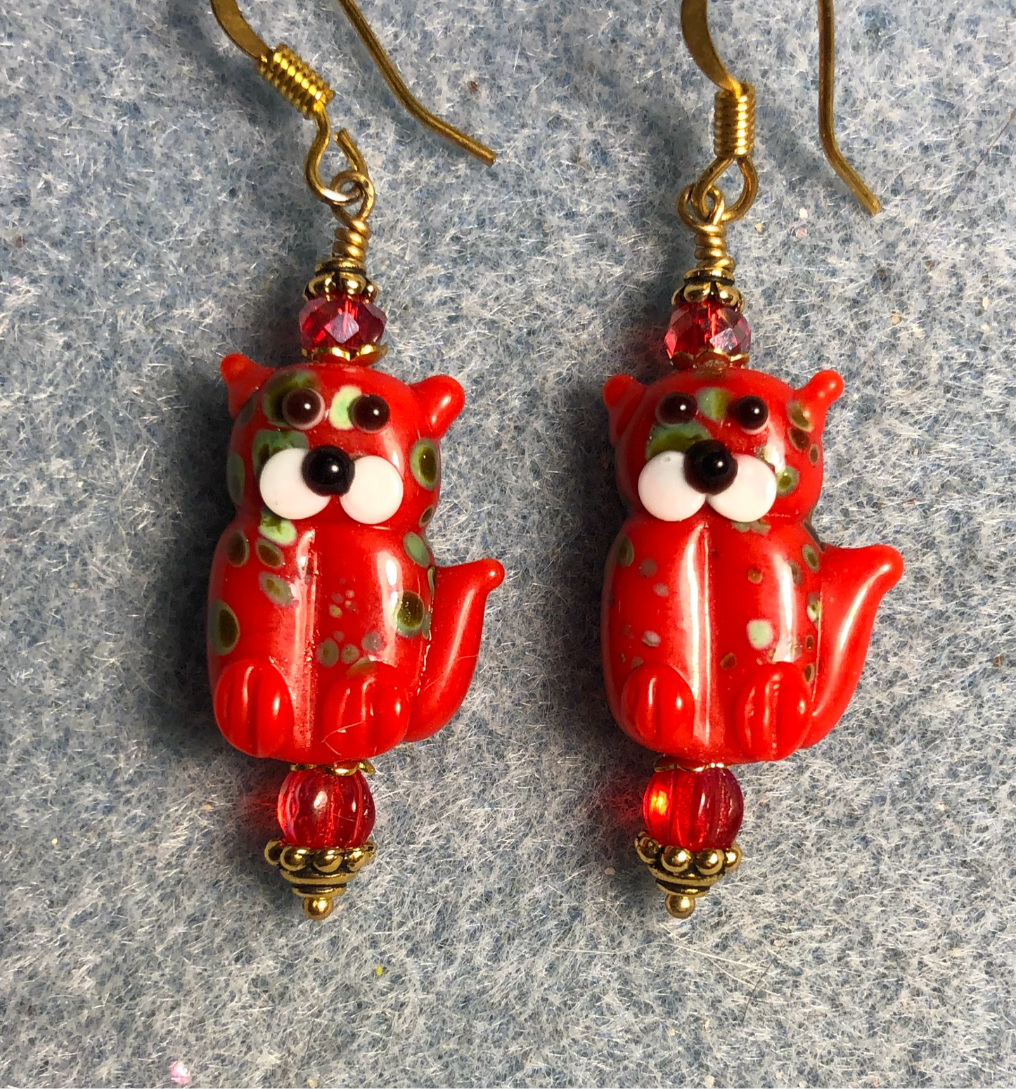 Opaque red lamp work cat bead earrings adorned with red Czech glass beads.