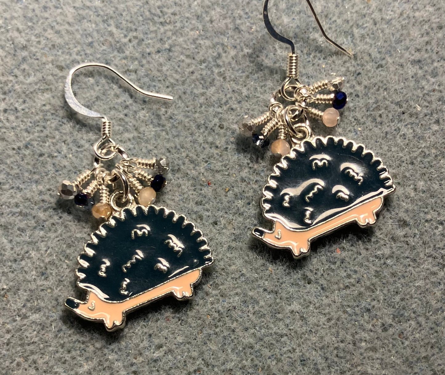 Dark blue and beige enamel hedgehog charm earrings adorned with tiny dangling dark blue, beige, and silver Chinese crystal beads.