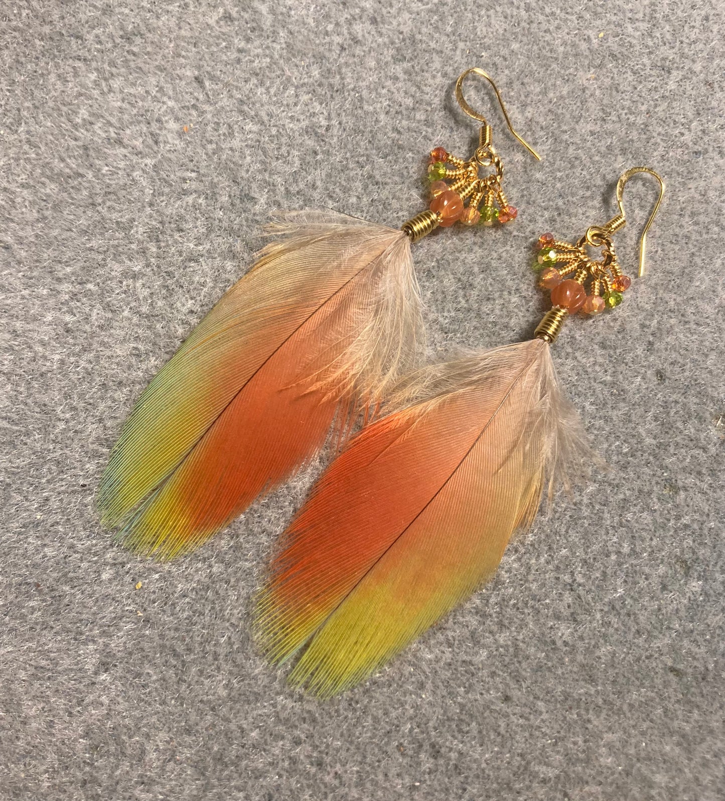 Rainbow scarlet macaw feather earrings adorned with orange Czech glass beads and tiny dangling orange, aqua, and green Chinese crystal beads.