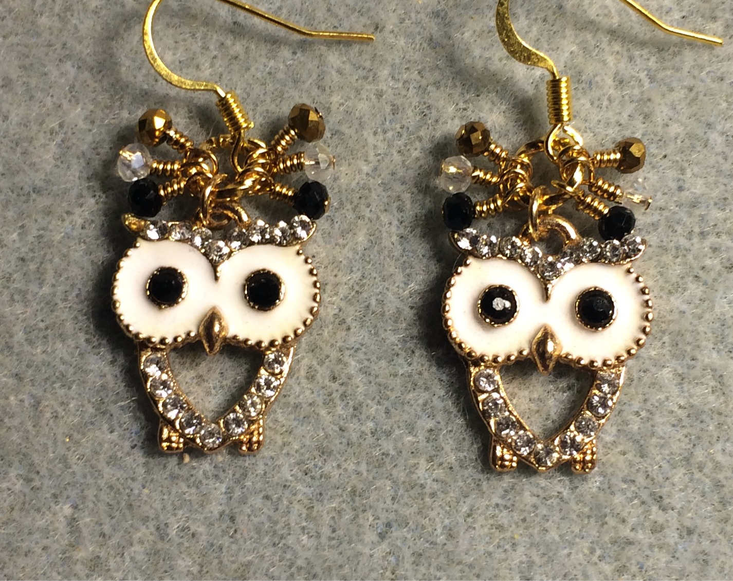 White, gold, and black enamel and rhinestone owl charm earrings adorned with tiny dangling clear, gold, and black Chinese crystal beads.