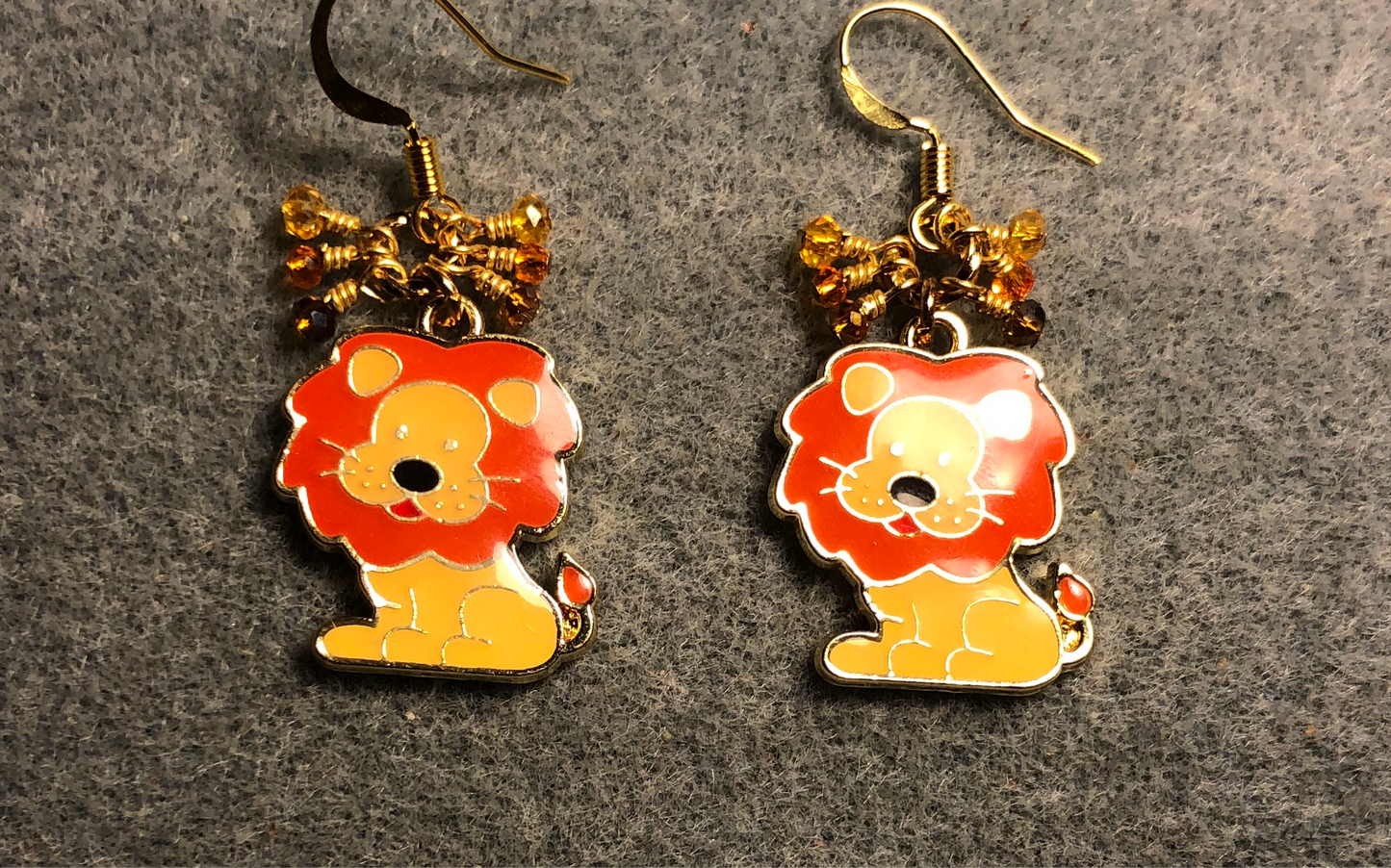 Amber and orange enamel lion charm earrings adorned with tiny dangling amber and orange Chinese crystal beads.
