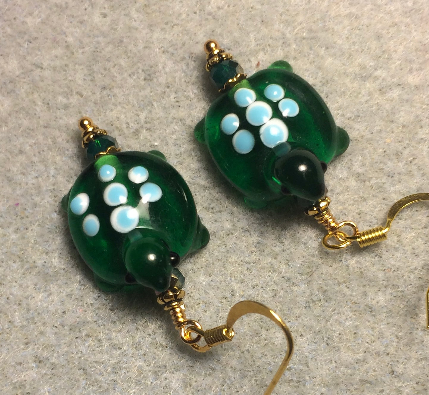 Dark green with blue spots lamp work turtle bead earrings adorned with dark green Chinese crystal beads.