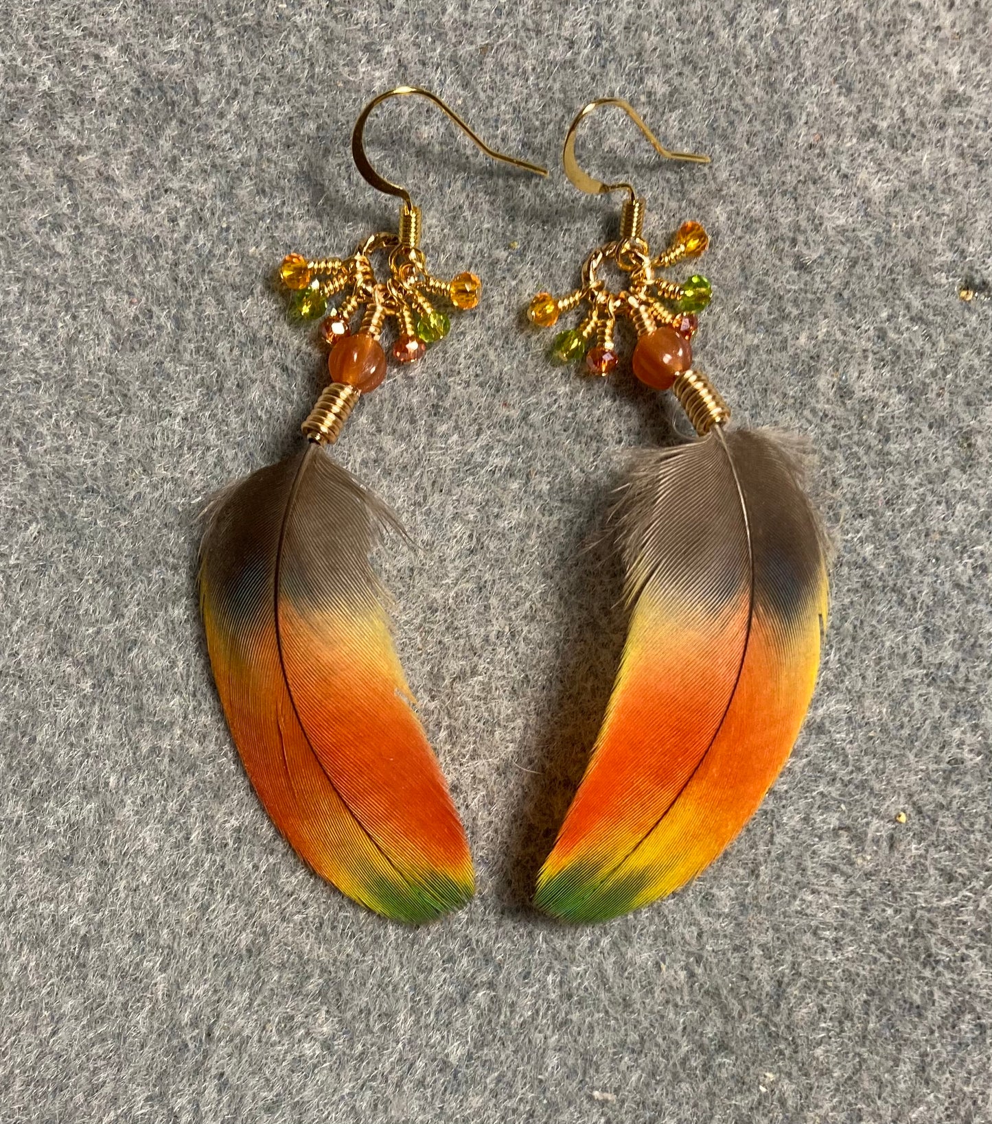 Bright yellow and orange scarlet macaw feather earrings adorned with tiny dangling orange, green, and amber Chinese crystal beads.