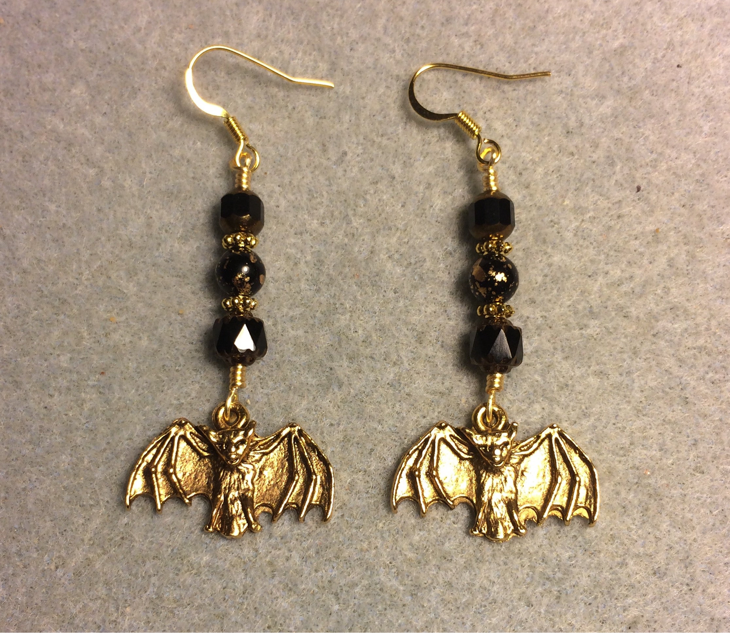 Gold bat charm earrings adorned with black Czech glass beads