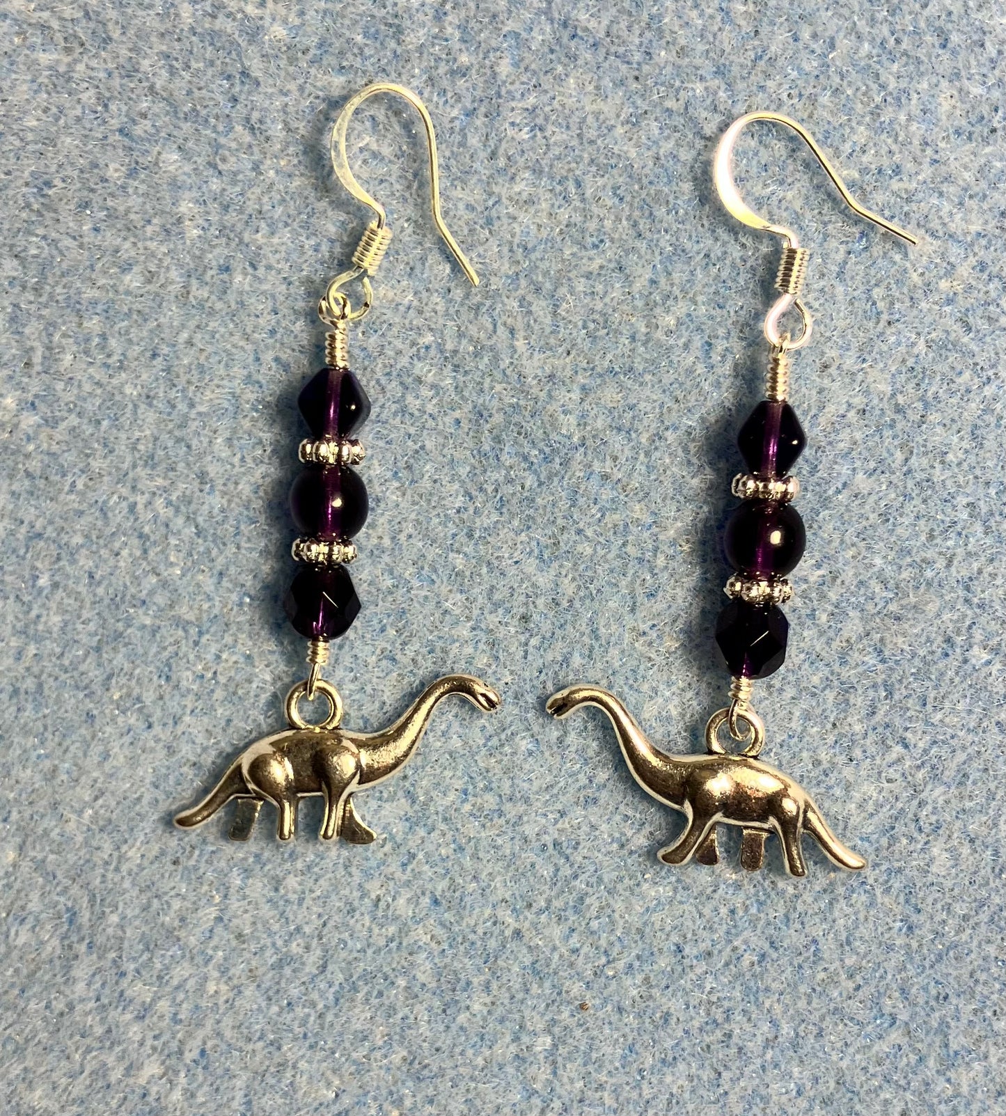 Silver brontosaurus charm earrings adorned with grape purple Czech glass beads.