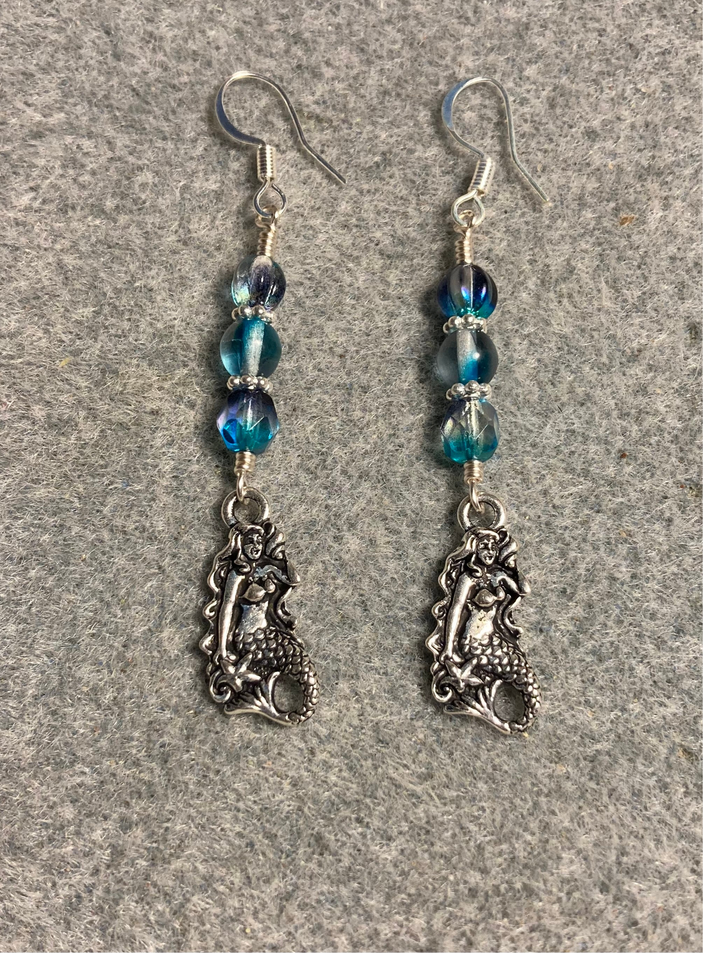Silver Tierracast mermaid charm earrings adorned with turquoise Czech glass beads.