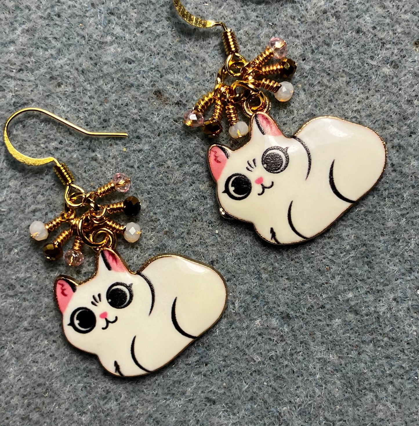 White, black, and pink enamel cat charm earrings adorned with tiny dangling white, black, and pink Chinese crystal beads.