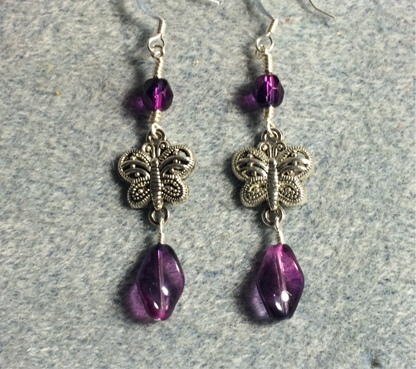 Silver filigree butterfly connector charm earrings adorned with purple Czech glass twist beads and purple Czech glass beads.