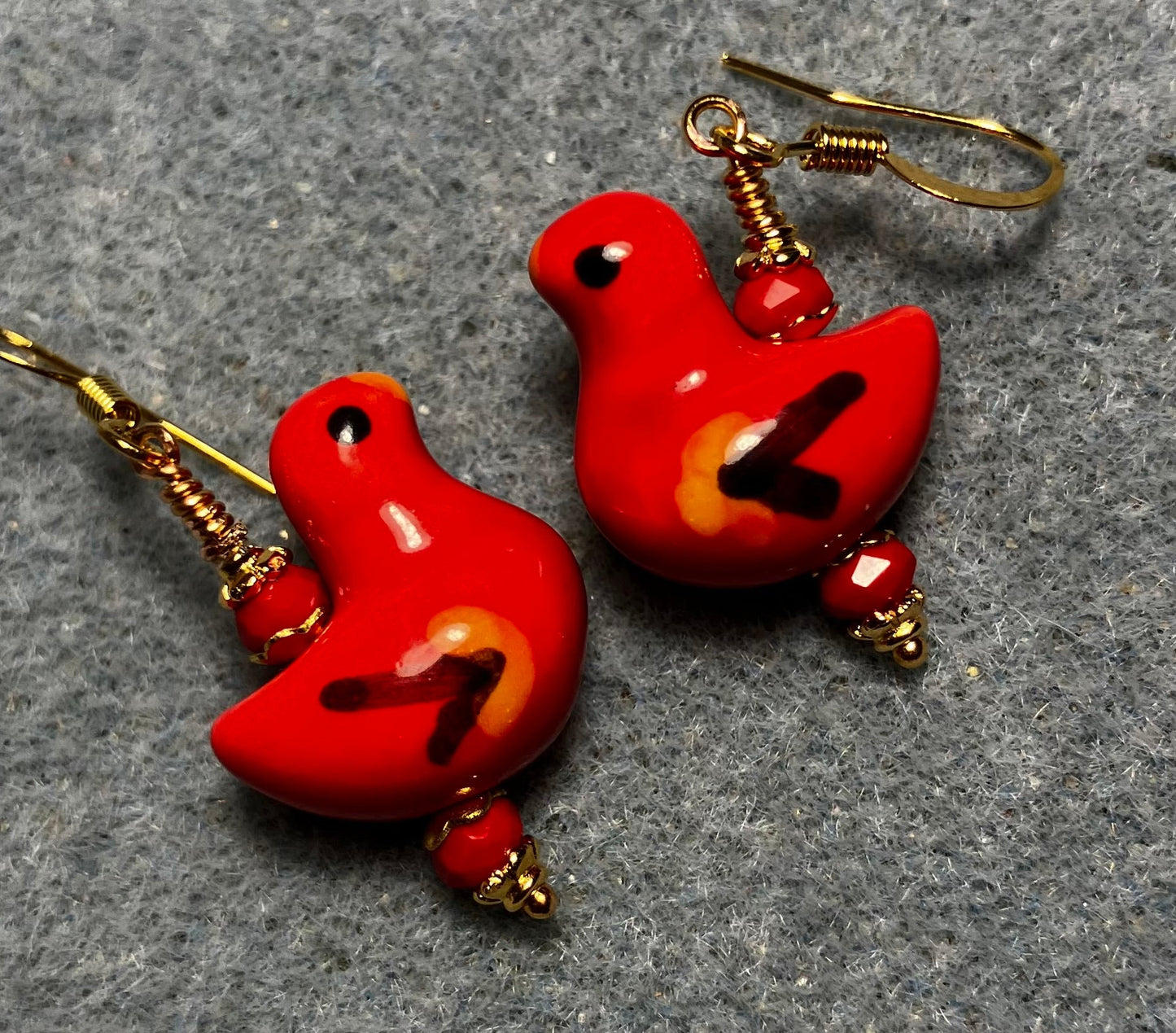 Red, black, and yellow ceramic duck bead earrings adorned with red Chinese crystal beads.
