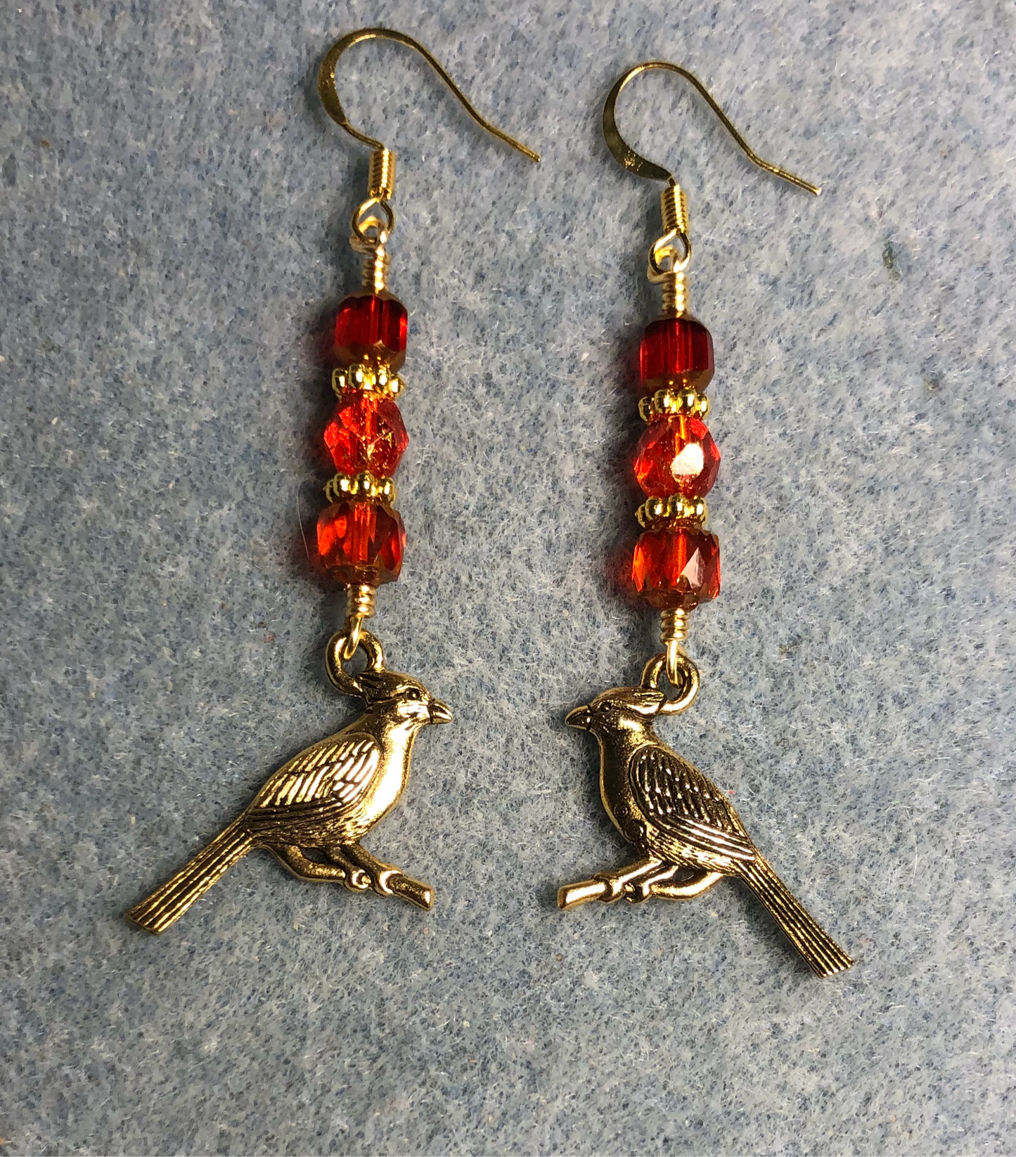 Gold cardinal charm earrings adorned with red Czech glass beads
