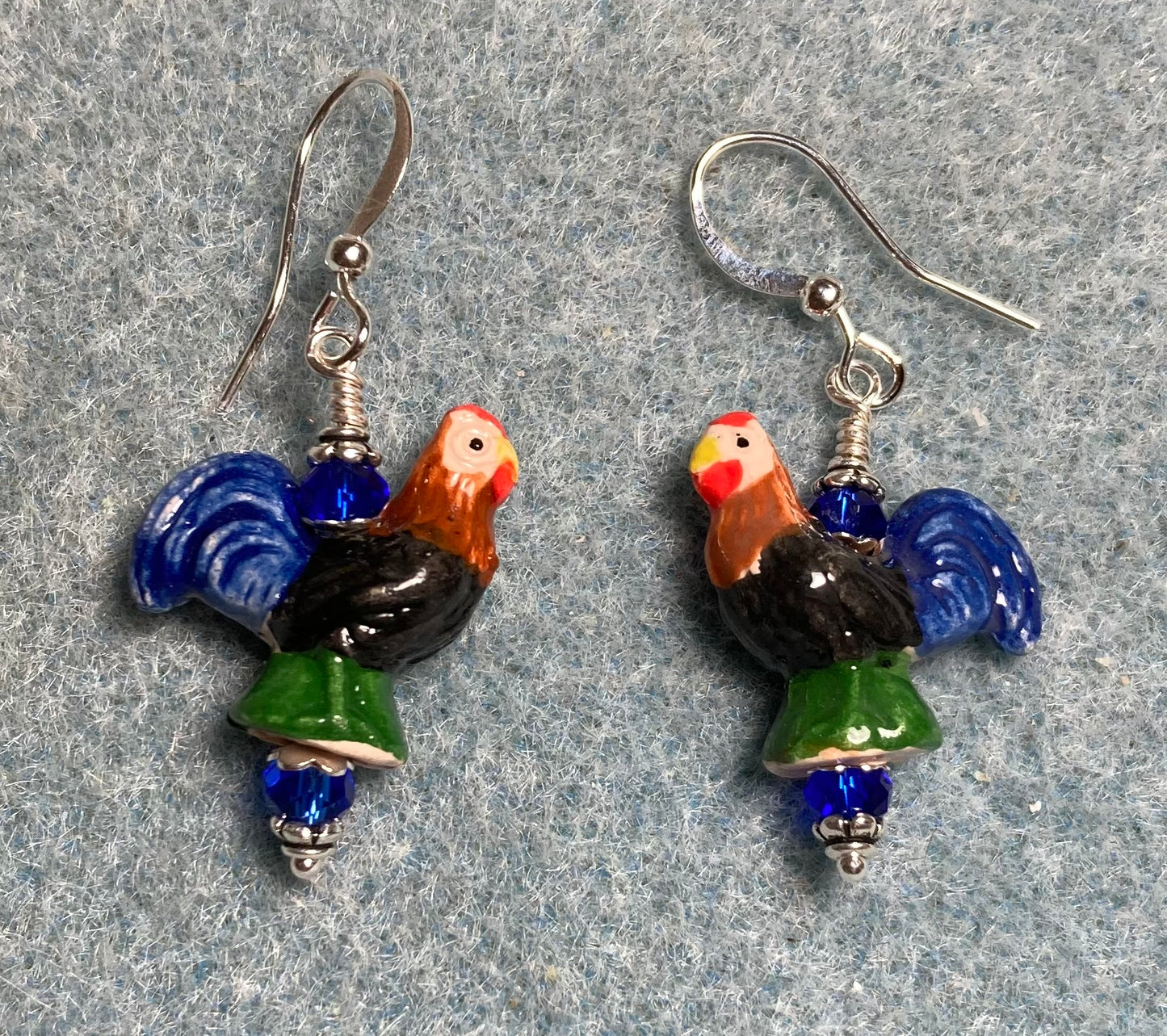 Small dark blue, black, green, and red ceramic chicken bead earrings adorned with dark blue Chinese crystal beads.