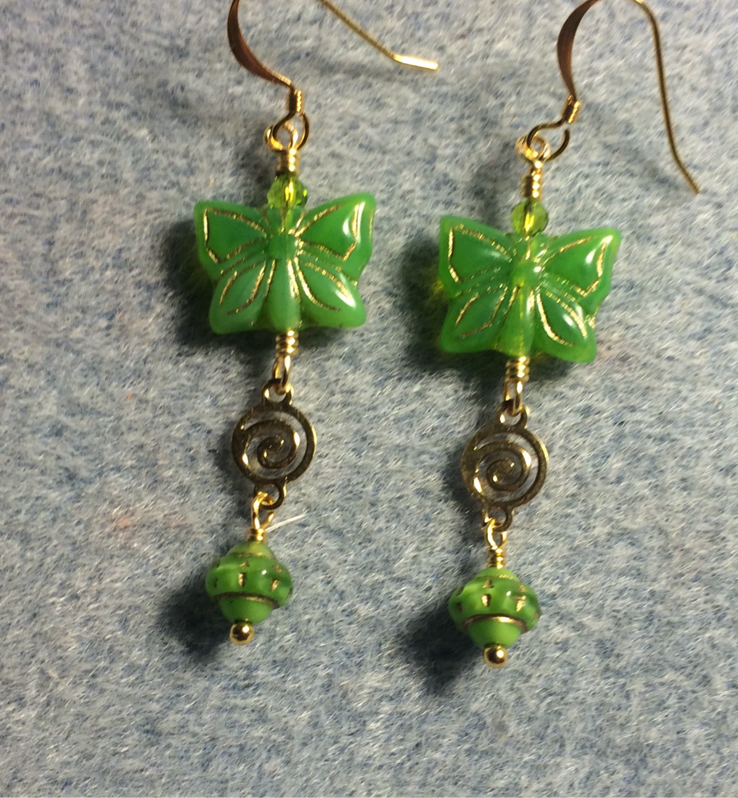 Bright green Czech glass butterfly bead earrings adorned with gold swirly connectors and bright green Czech glass Saturn beads.