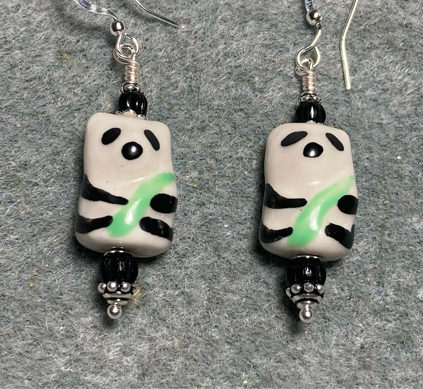 Black, white, and green ceramic panda bear bead earrings adorned with black Czech glass beads.