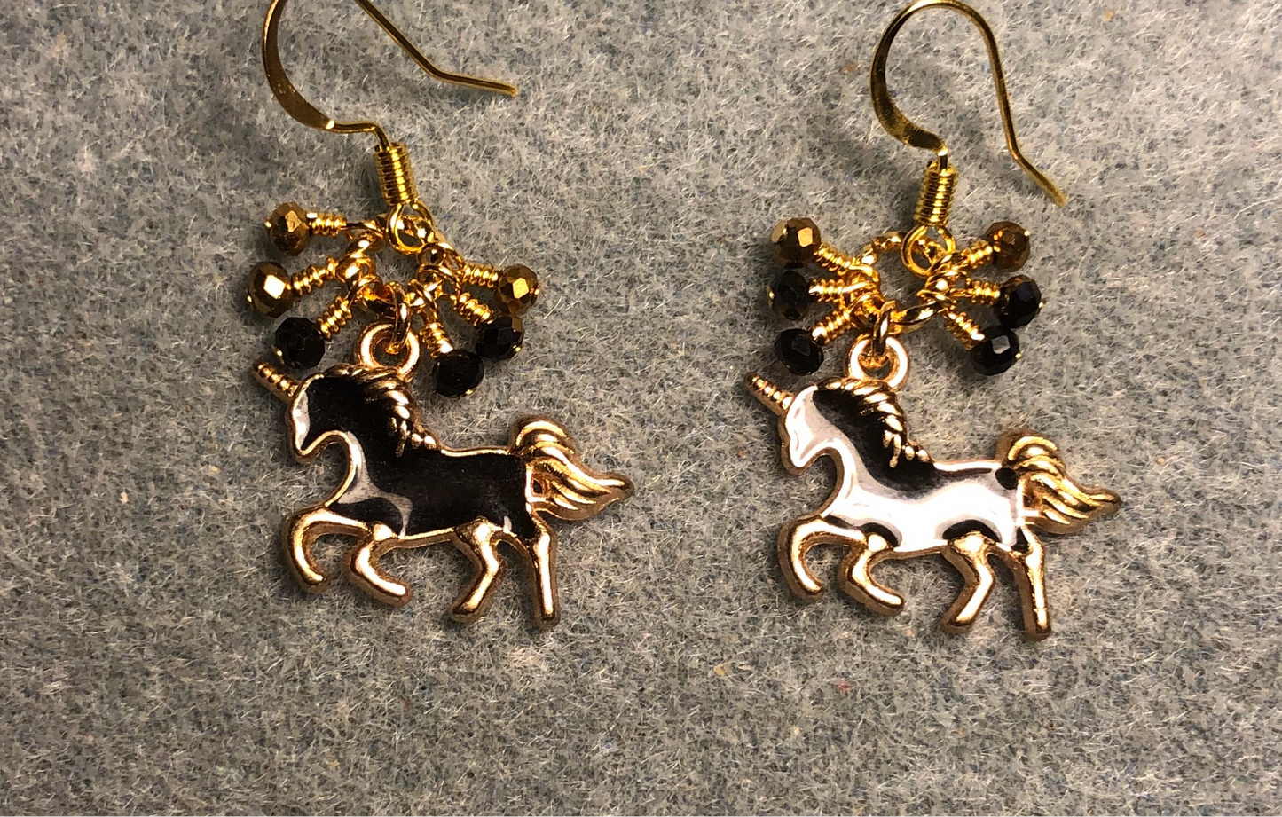 Small black and gold enamel unicorn charm earrings adorned with tiny dangling black and gold Chinese crystal beads.