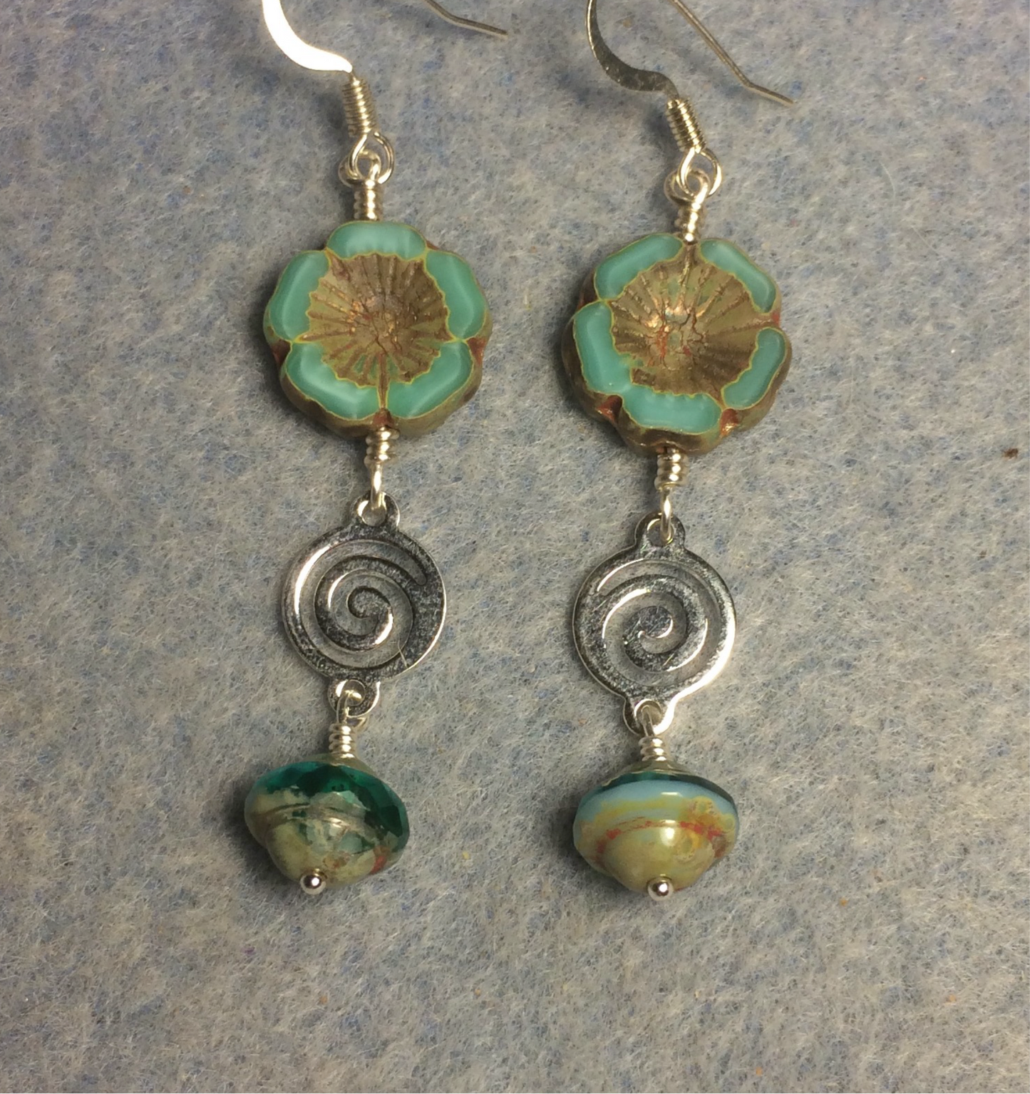 Turquoise green Czech glass pansy bead earrings adorned with silver swirly connectors and turquoise green Czech glass Saturn beads.