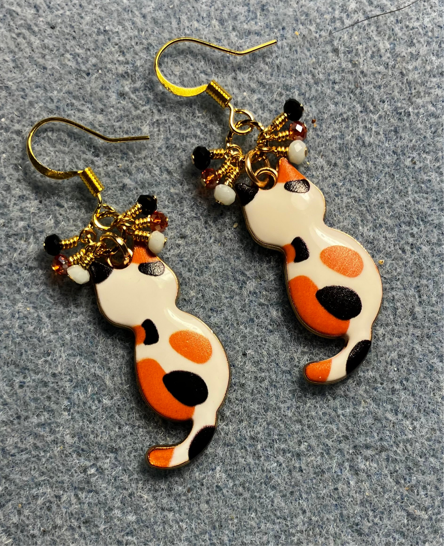 Orange, white, and black enamel calico cat charm earrings adorned with tiny dangling orange, white, and black Chinese crystal beads.