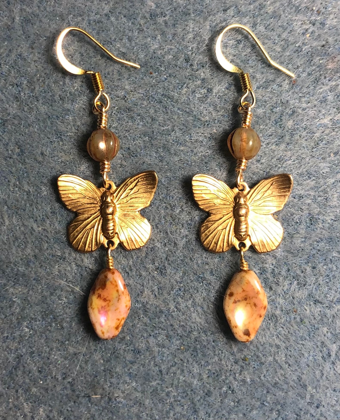 Gold butterfly charm connector earrings adorned with beige Picasso Czech glass twist beads and beige Picasso Czech glass beads.