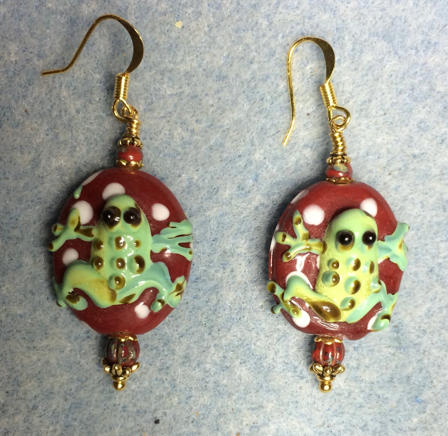 Dark red and green lamp work frog bead earrings adorned with dark red Picasso Czech glass beads.