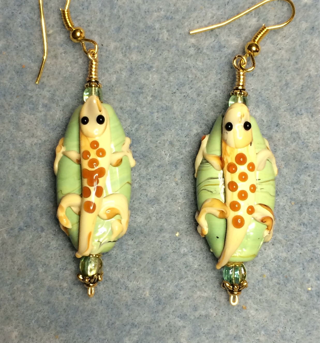 Light green, yellow, and orange lamp work lizard bead earrings adorned with light green Czech glass beads.