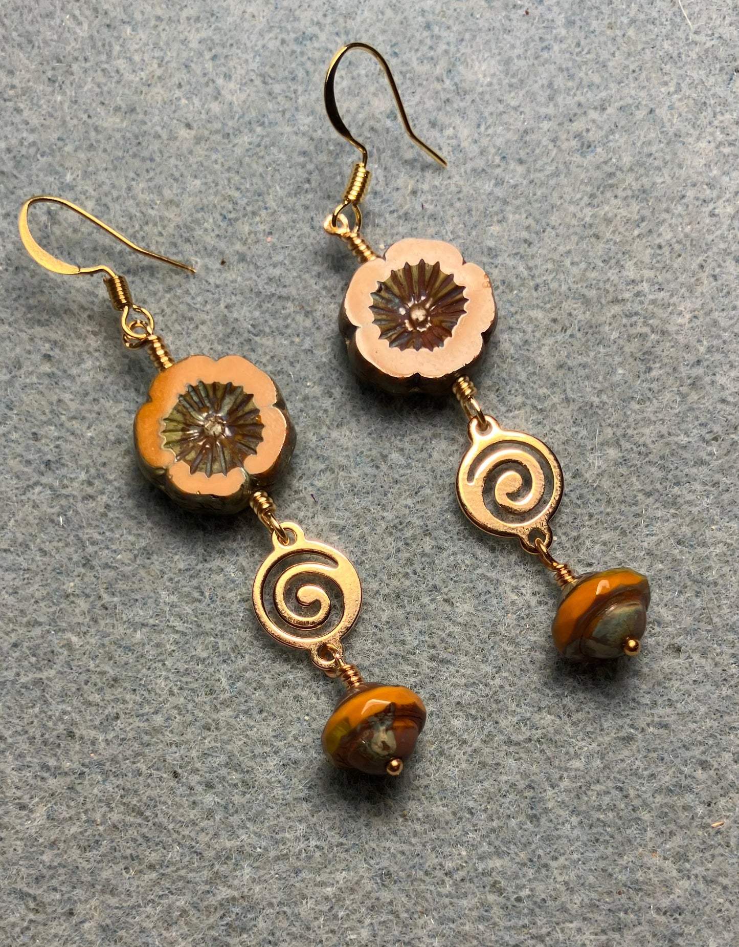 Mustard yellow Czech glass pansy bead earrings adorned with gold swirly connectors and mustard yellow Czech glass Saturn beads.