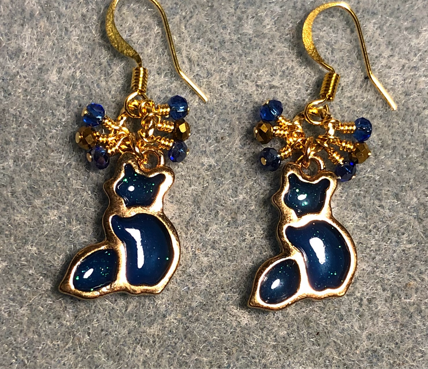 Dark blue and gold sparkly resin cat charm earrings adorned with small dangling dark blue and gold Chinese crystal beads.