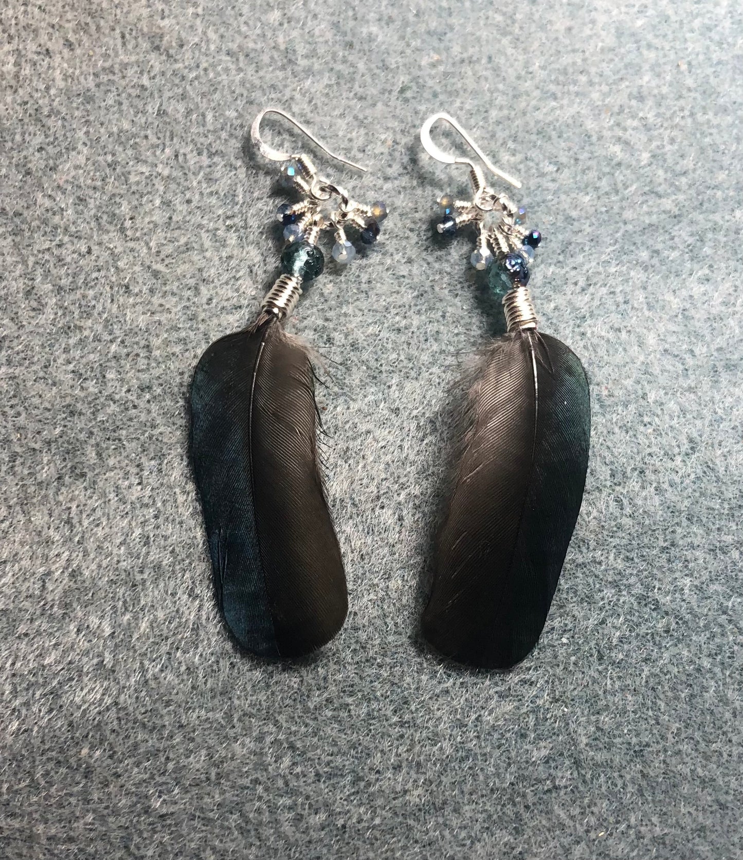 Small blue magpie feather earrings adorned with small blue Czech glass beads and tiny dangling blue Chinese crystal beads.