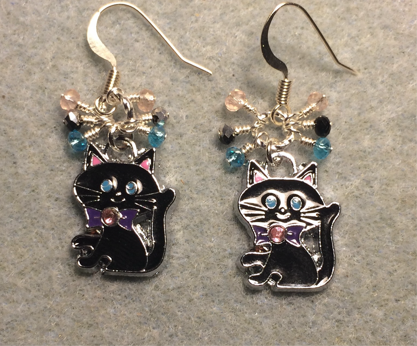 Black, turquoise, and pink enamel cat charm earrings adorned with tiny dangling black, turquoise, and pink beads.