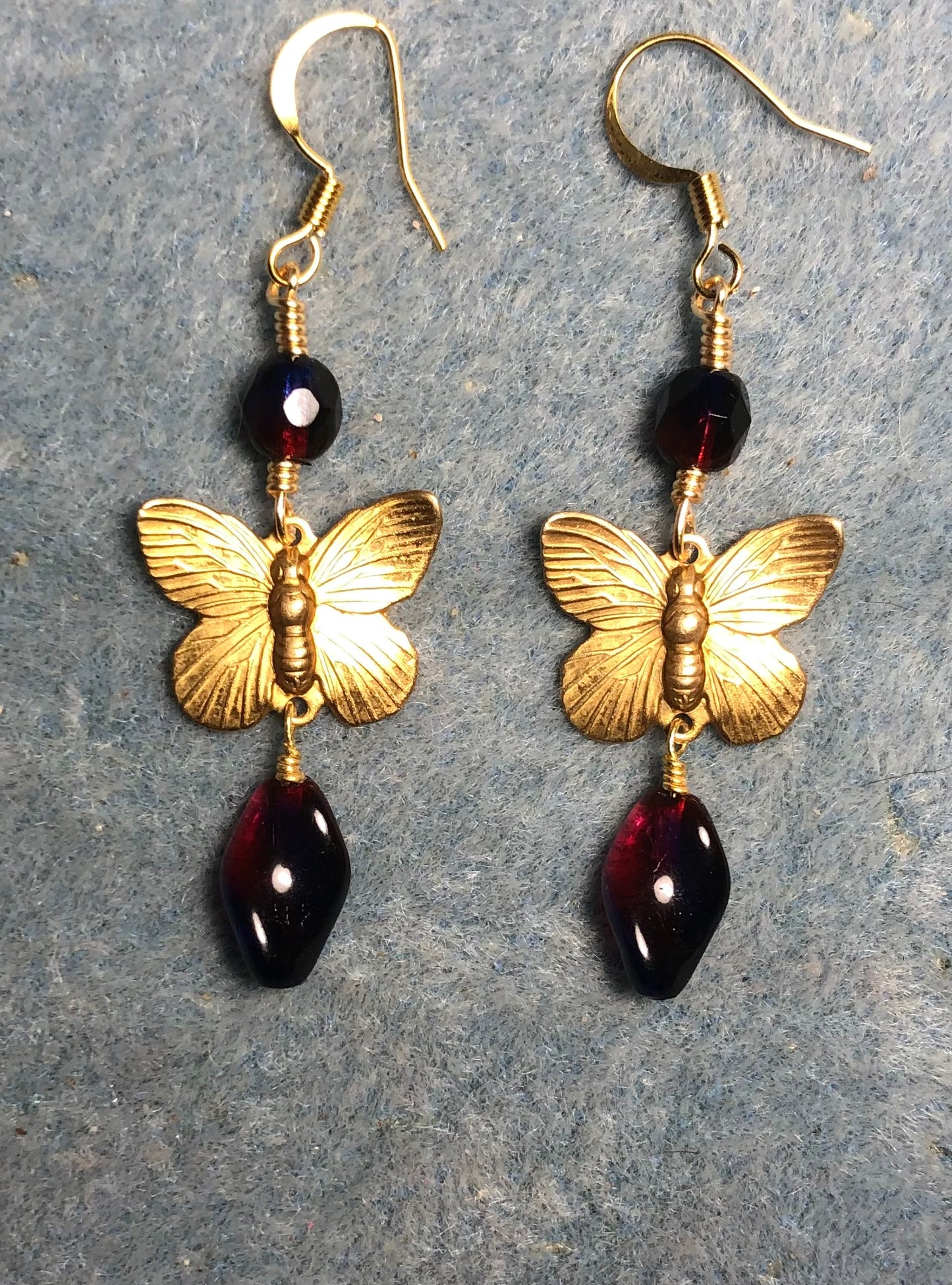 Gold butterfly charm connector earrings adorned with red purple Czech glass twist beads and red purple Czech glass beads.