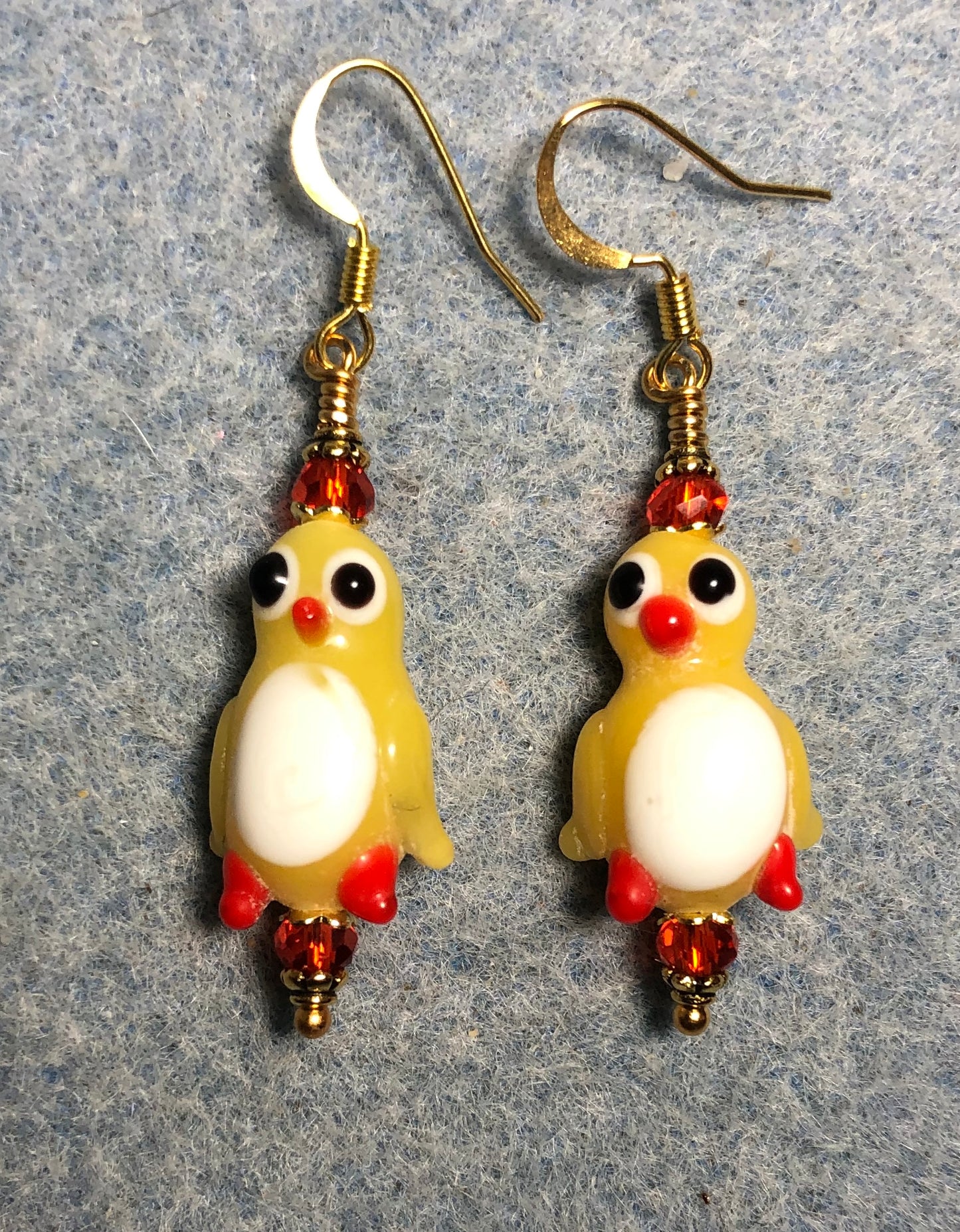Yellow, white, and red lamp work duck bead earrings adorned with red Chinese crystal beads.