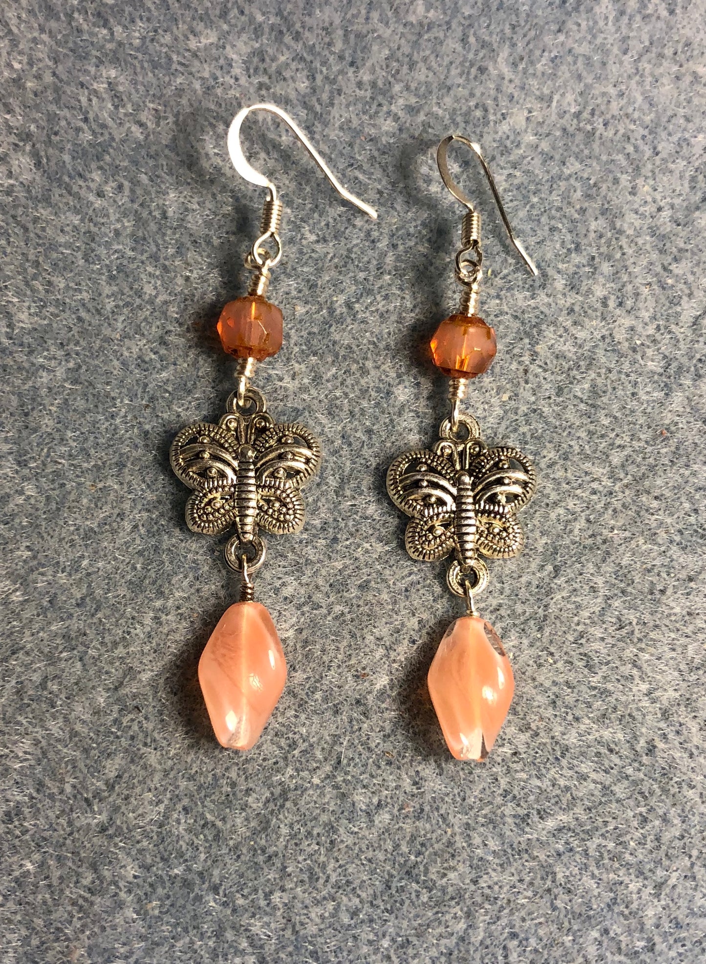 Silver filigree butterfly connector charm earrings adorned with salmon Czech glass twist beads and salmon Czech glass beads.