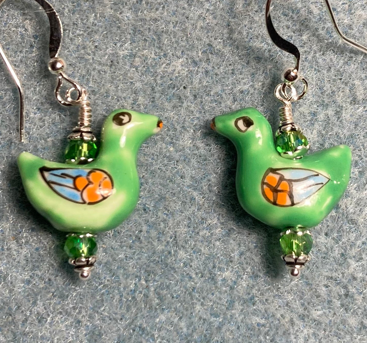 Green, orange, and blue ceramic duck bead earrings adorned with green Chinese crystal beads.