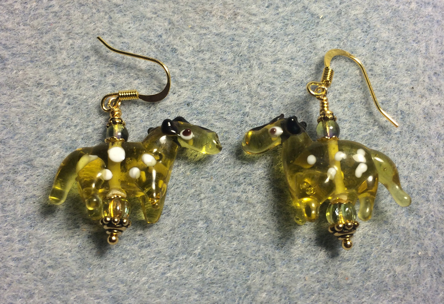 Translucent greenish amber lamp work spotted horse bead earrings adorned with olive green Czech glass beads.
