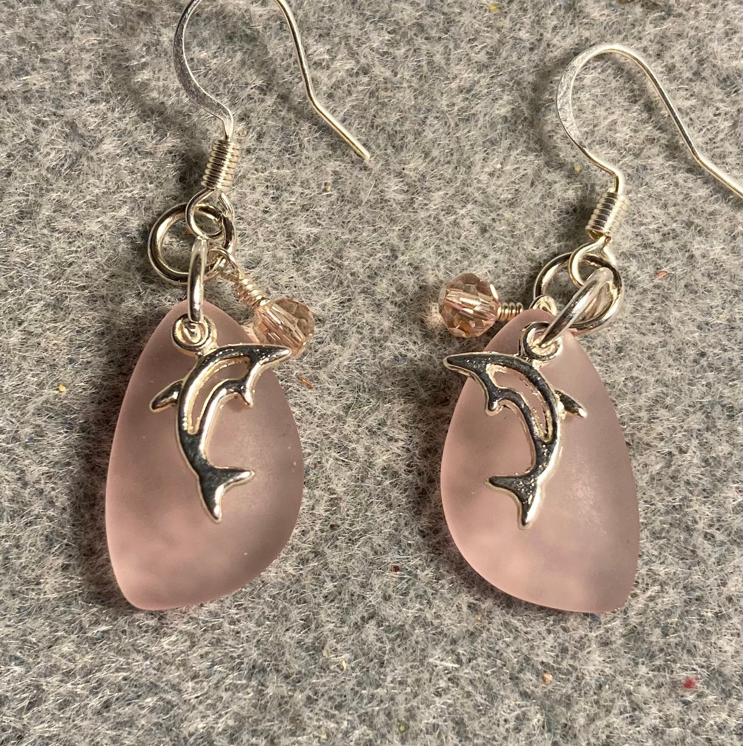 Small pink sea glass pendant bead earrings adorned with small silver dolphin charms and small pink Chinese crystal beads.