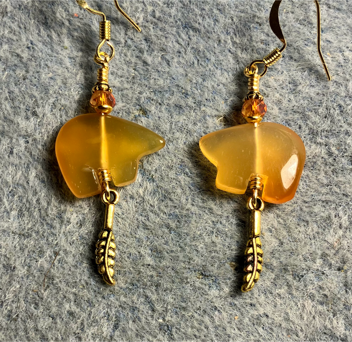 Carnelian gemstone Zuni bear fetish bear earrings adorned with orange crystal beads and tiny gold feather charms.