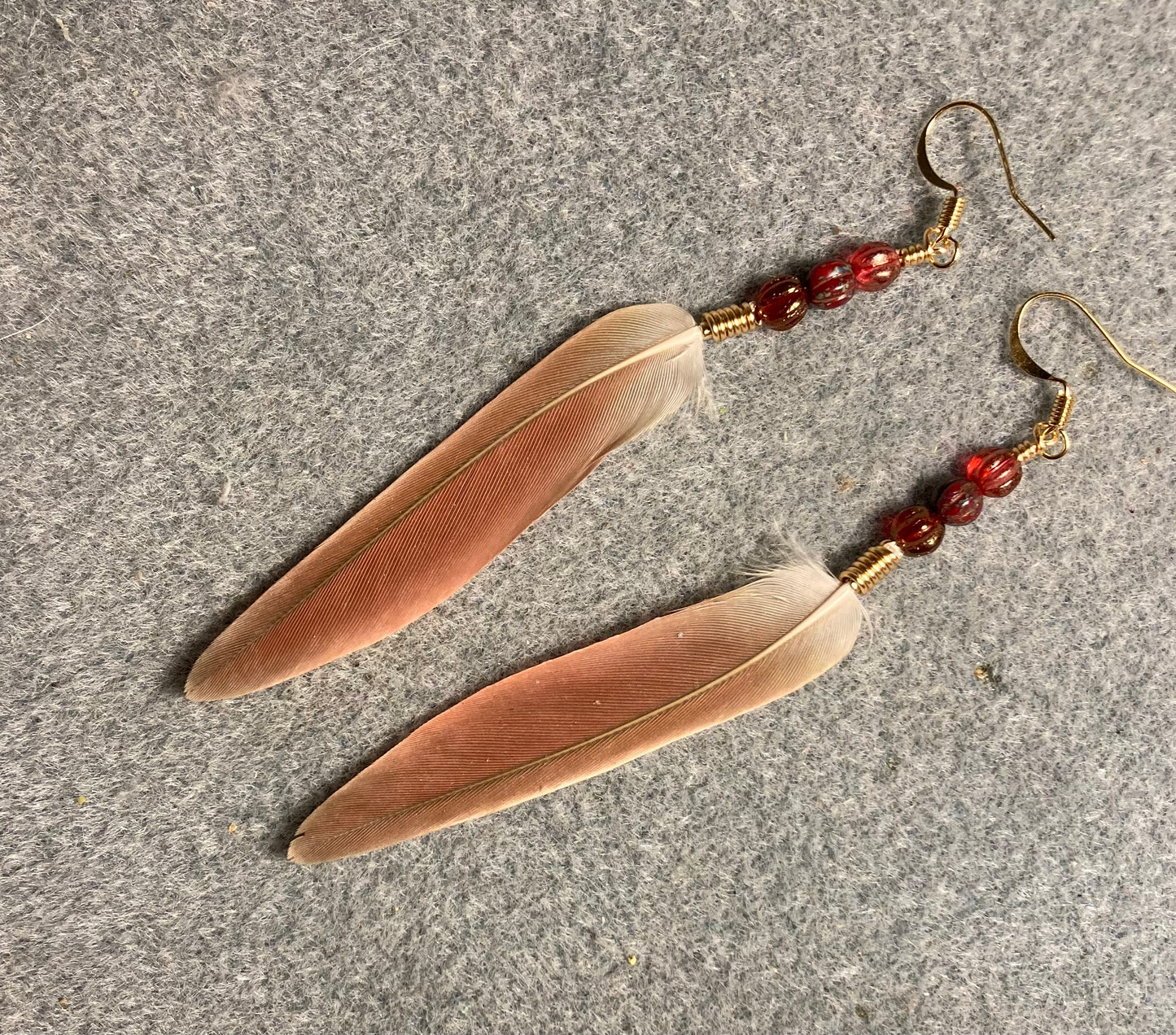 Light red green cheeked conure tail feather earrings adorned with light red Czech glass beads