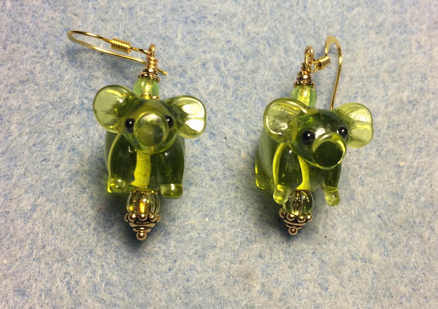 Translucent olive green lamp work pig bead earrings adorned with olive green Czech glass beads.