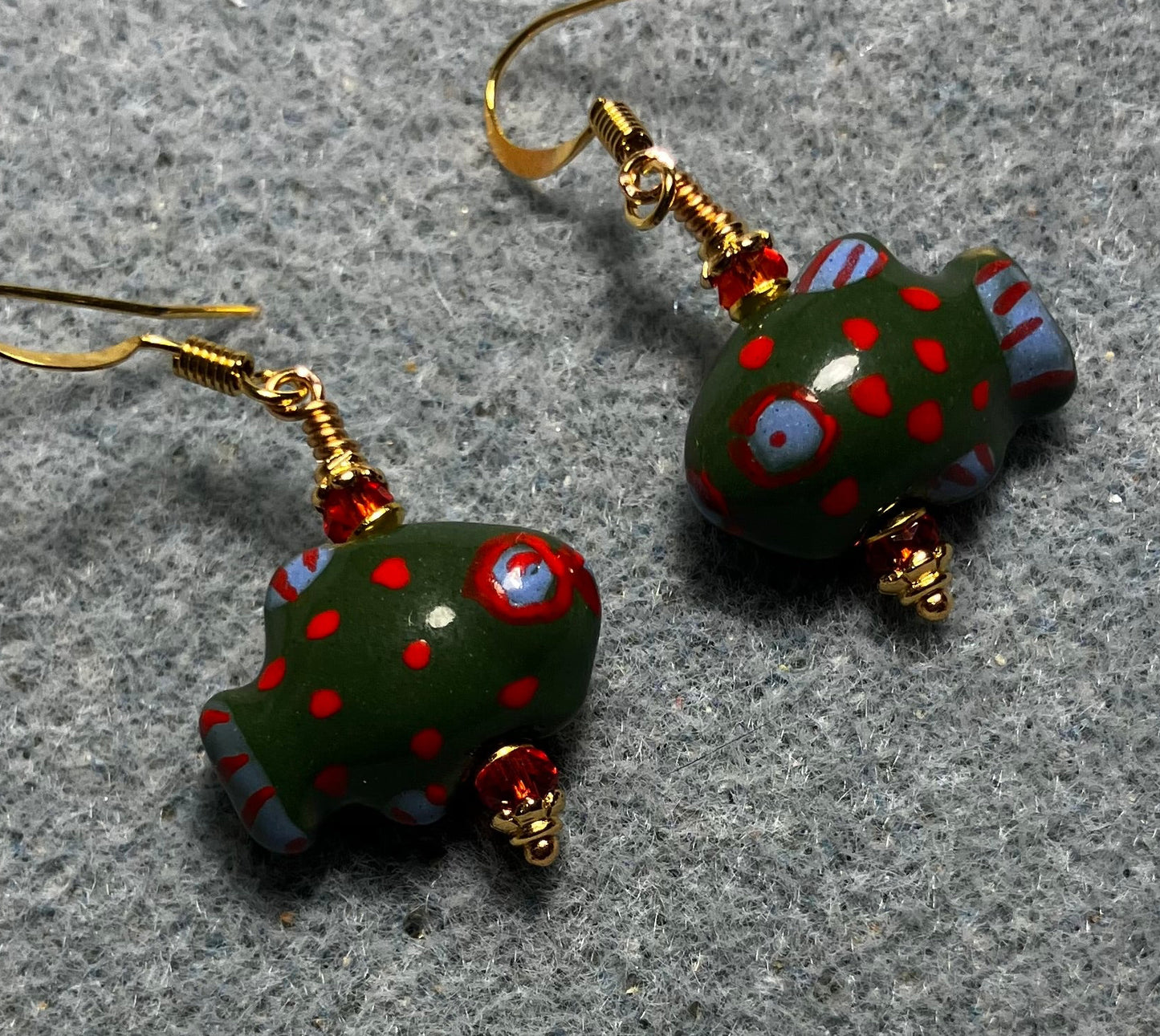 Dark green, red, and blue ceramic spotted fish bead earrings adorned with red Chinese crystal beads.