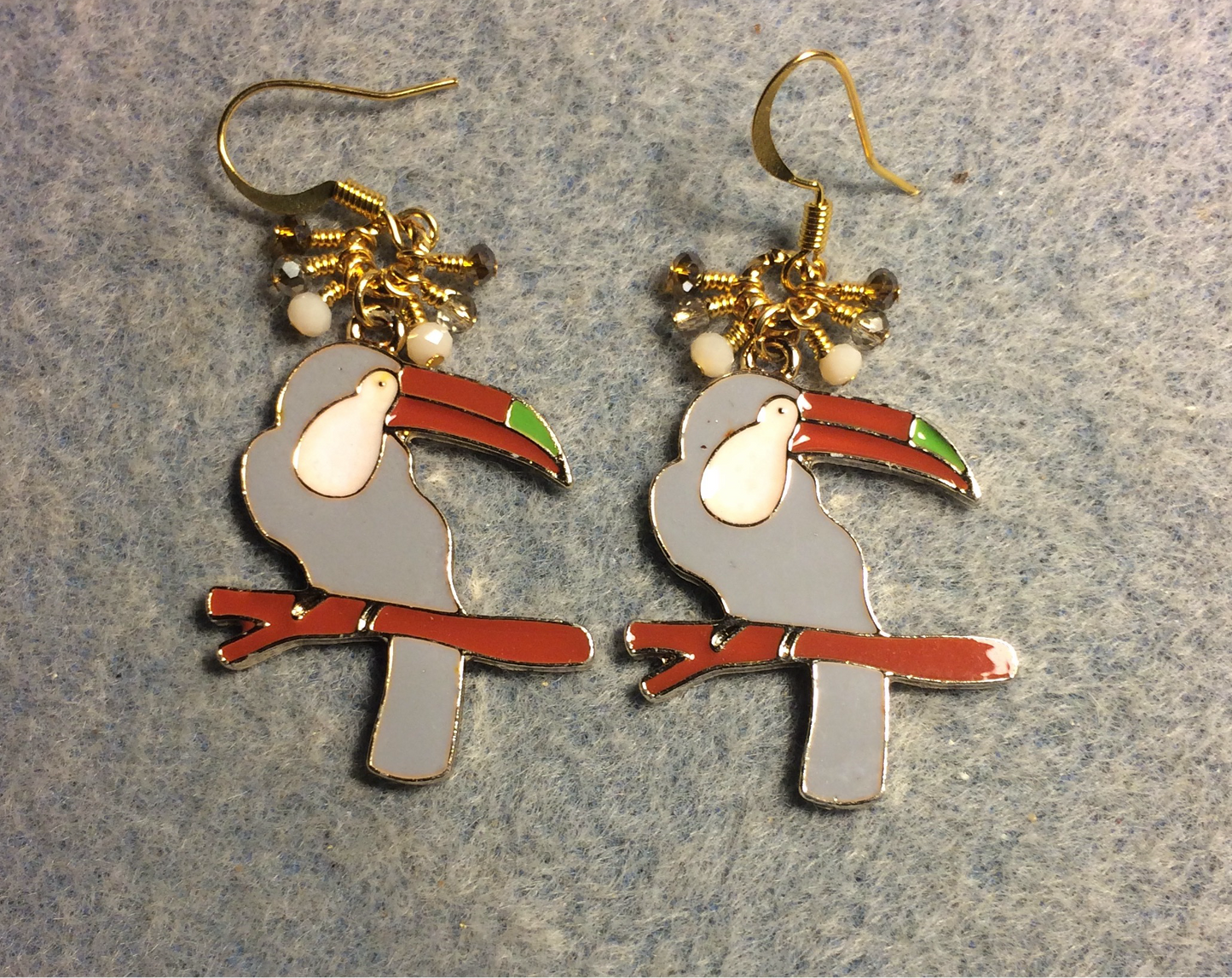 Gray, white, and brown enamel toucan charm earrings adorned with tiny dangling gray, white, and brown Chinese crystal beads.