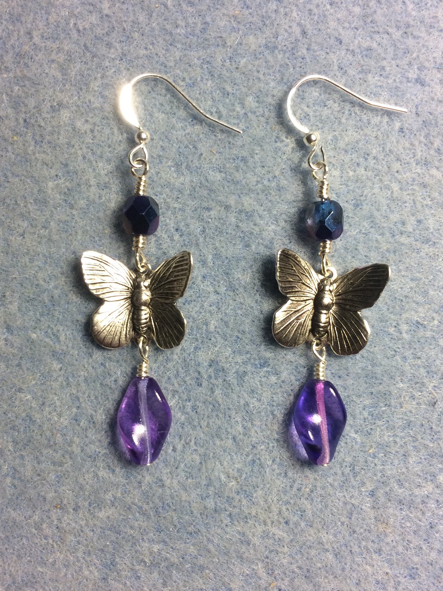 Silver butterfly charm connector earrings adorned with purple Czech glass twist beads and purple Czech glass beads.