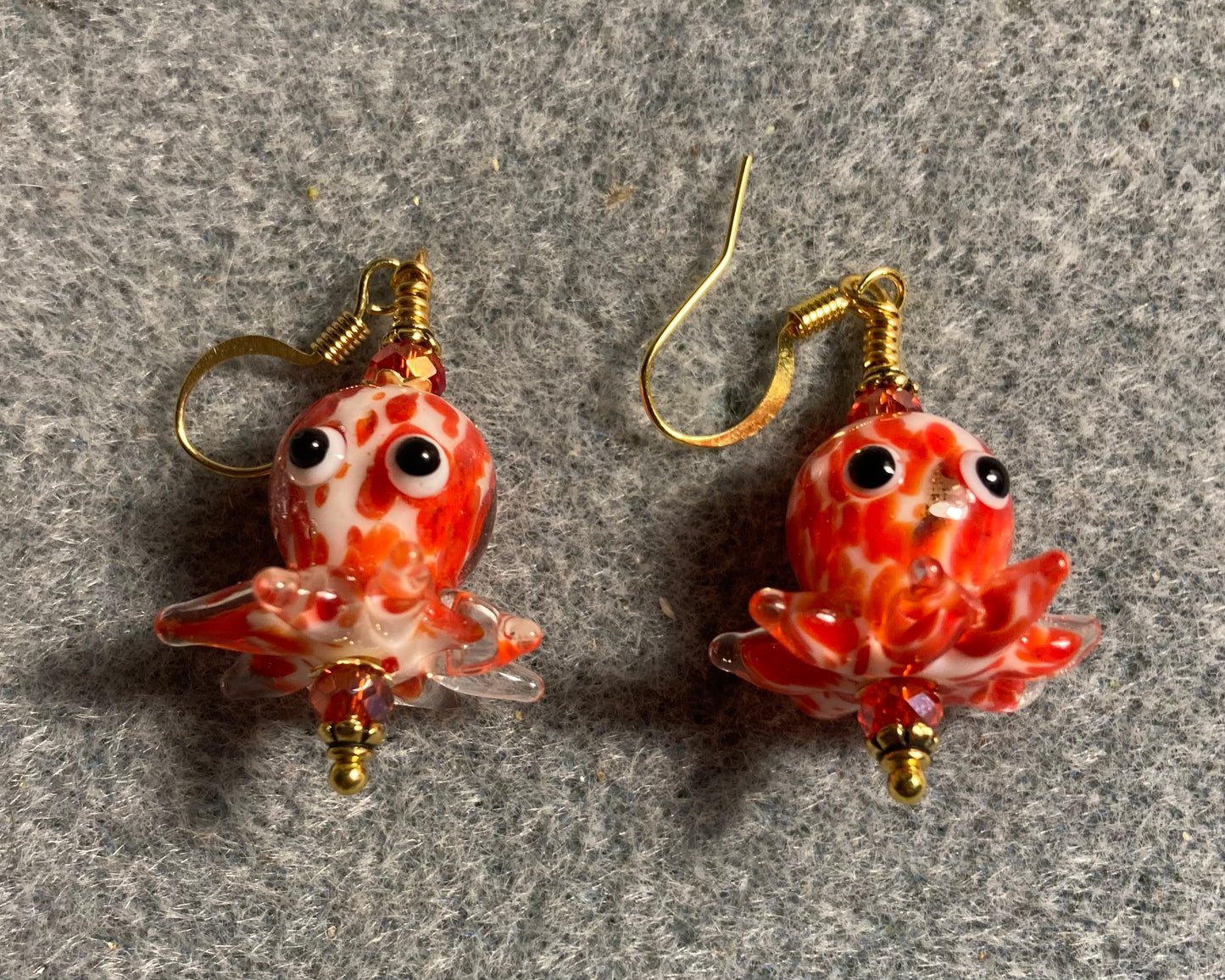 Red and white mottled lamp work octopus bead earrings adorned with red Chinese crystal beads.