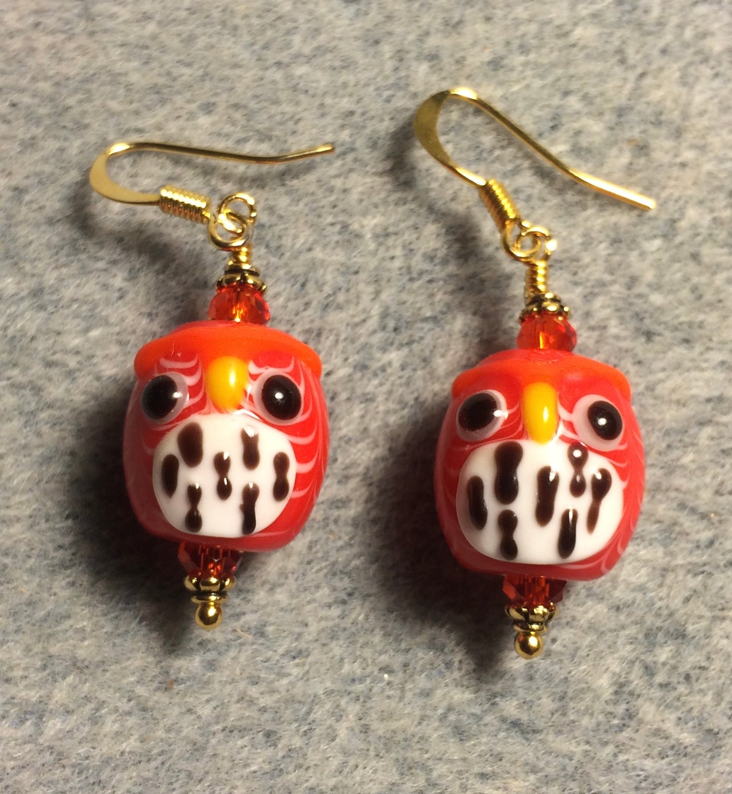 Orange red and white lamp work spotted owl bead earrings adorned with orange red Chinese crystal beads.
