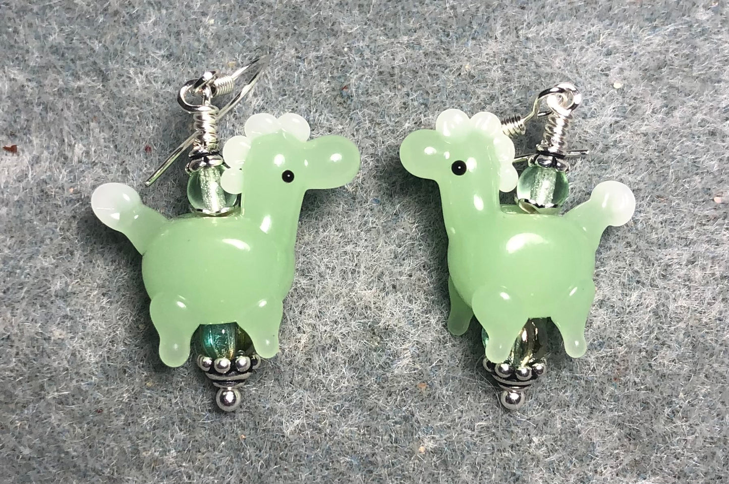 Opaque light green lamp work spotted horse bead earrings adorned with light green Czech glass beads.